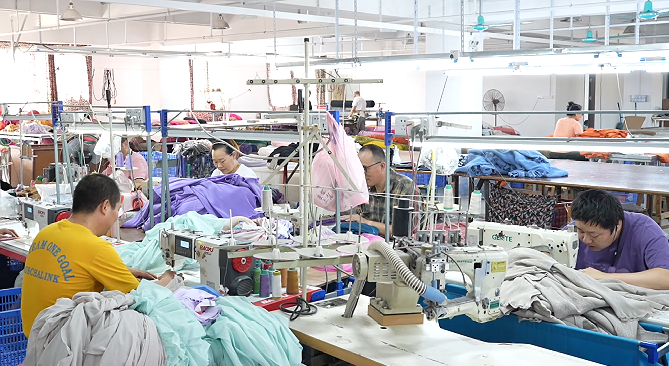 Workers sewing custom garments at a clothing factory in Dongguan, China