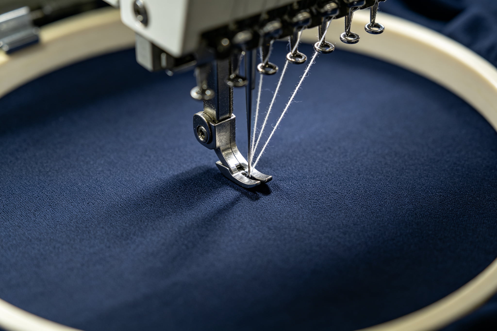 Industrial embroidery machine needle on blank dark navy fabric, professional embroidery service ready for custom design